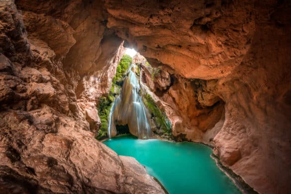 Una cascada de agua cristalina metida en una cueva